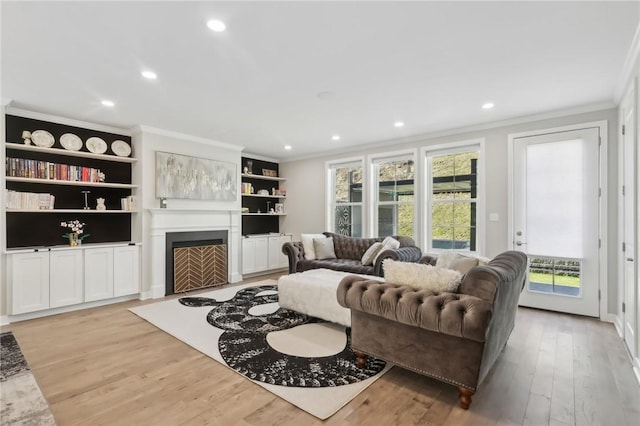 living area featuring recessed lighting, a fireplace, crown molding, and light wood finished floors