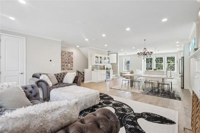 living room featuring recessed lighting, light wood-type flooring, an inviting chandelier, and ornamental molding