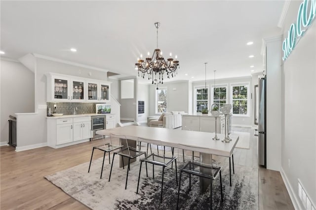 dining space with recessed lighting, light wood-type flooring, beverage cooler, and ornamental molding