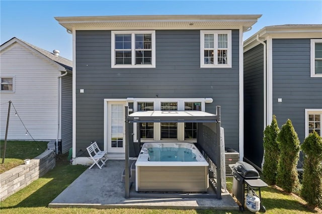 rear view of property featuring a patio area and a hot tub