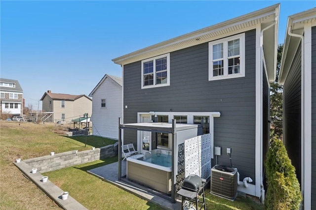 rear view of house with a lawn, central AC unit, and a hot tub