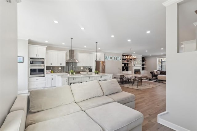 living area with ornamental molding, recessed lighting, light wood-type flooring, and baseboards