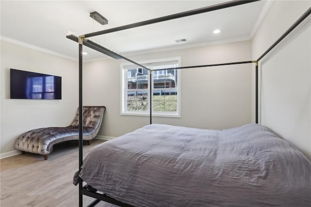 bedroom with visible vents, crown molding, baseboards, and wood finished floors