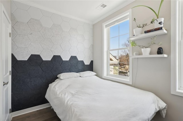 bedroom featuring crown molding, wood finished floors, visible vents, and baseboards