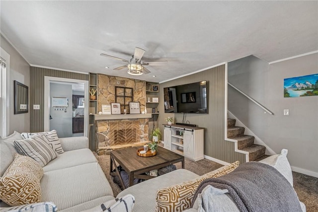 living area featuring a stone fireplace, crown molding, carpet flooring, and stairs