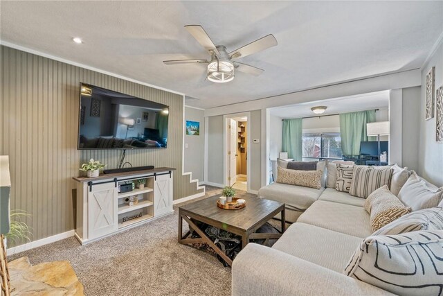 living room with baseboards, carpet, ceiling fan, and crown molding