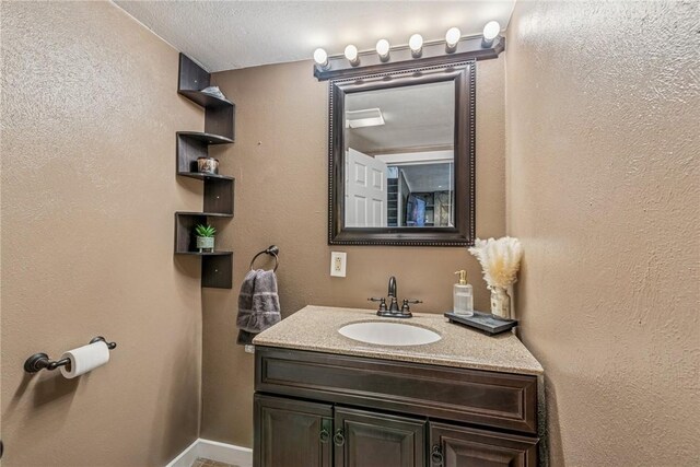 bathroom featuring vanity, a textured wall, and baseboards