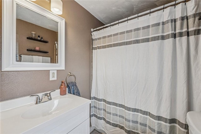 full bathroom with a shower with curtain, toilet, vanity, and a textured wall