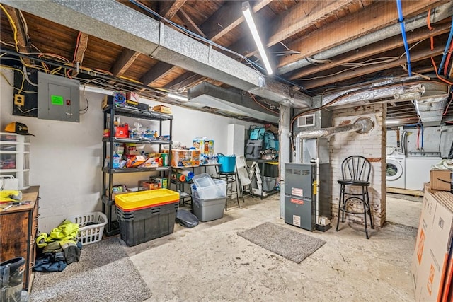 unfinished below grade area with heating unit, electric panel, visible vents, and washing machine and clothes dryer