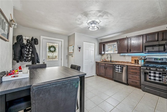 kitchen with a sink, stainless steel appliances, dark brown cabinets, a textured ceiling, and backsplash