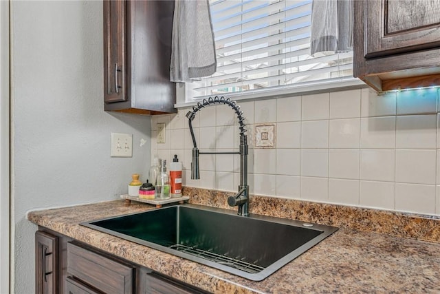 kitchen with tasteful backsplash, dark brown cabinetry, and a sink