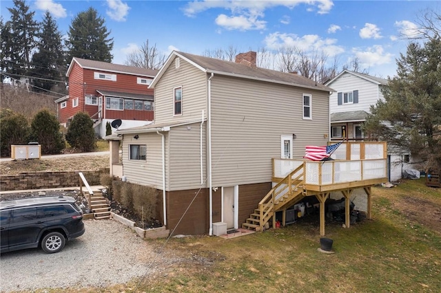 back of house featuring stairs, a wooden deck, a yard, and a chimney