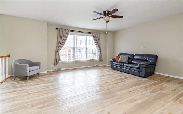 sitting room with light wood finished floors, a ceiling fan, and baseboards