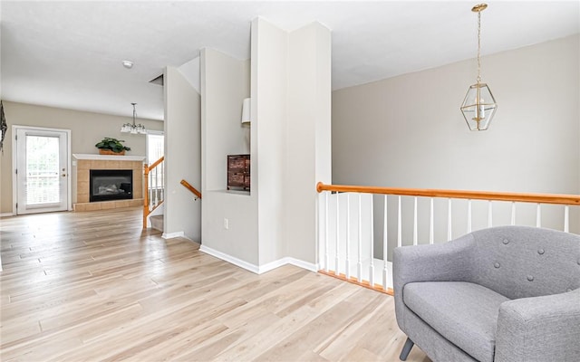 living area with stairs, baseboards, light wood finished floors, and a tile fireplace