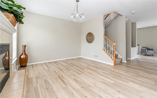 unfurnished living room with visible vents, baseboards, light wood-type flooring, stairs, and a tile fireplace