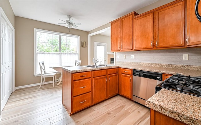 kitchen with light countertops, light wood-style flooring, stainless steel dishwasher, brown cabinetry, and a sink