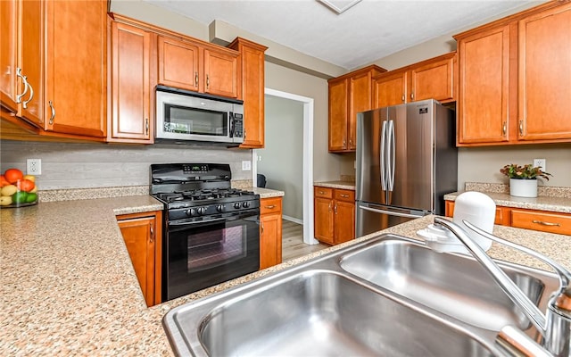 kitchen featuring brown cabinets, appliances with stainless steel finishes, light countertops, and a sink