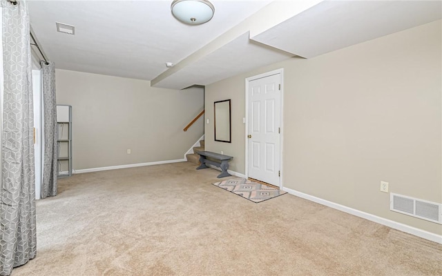 finished below grade area with visible vents, carpet flooring, stairway, and baseboards