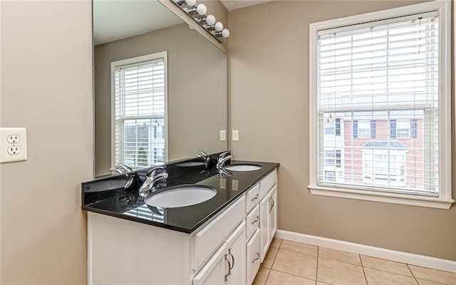 bathroom with a sink, baseboards, double vanity, and tile patterned floors