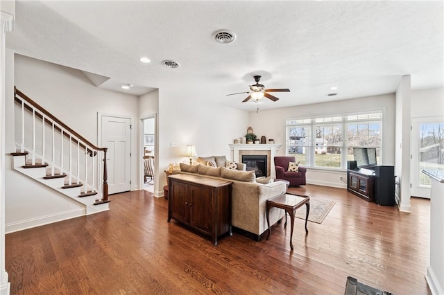 living room with visible vents, a glass covered fireplace, and wood finished floors