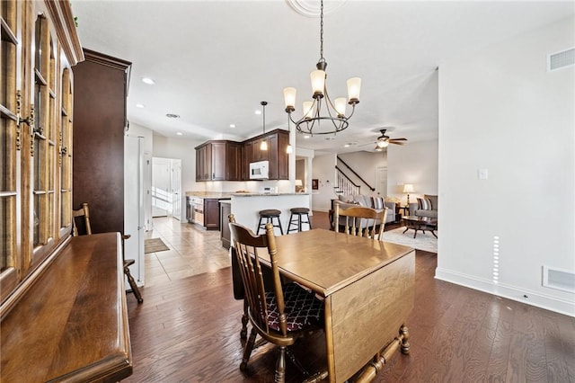 dining space with baseboards, visible vents, recessed lighting, dark wood-type flooring, and ceiling fan with notable chandelier