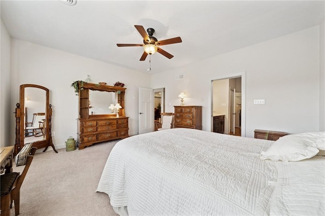 bedroom featuring ensuite bath, light colored carpet, visible vents, and ceiling fan