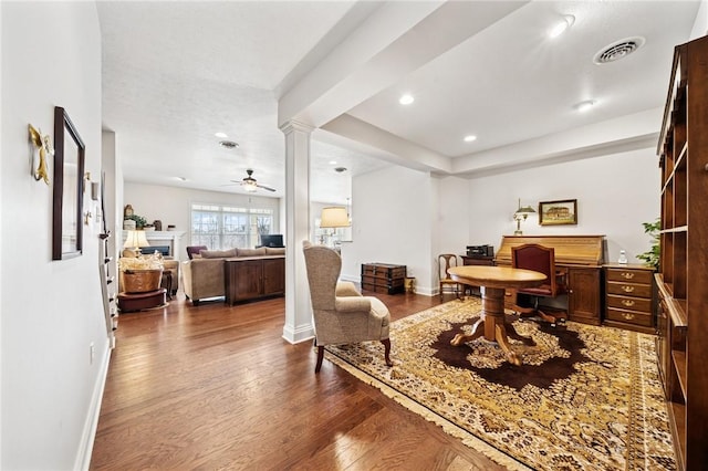 office featuring dark wood-type flooring, baseboards, decorative columns, a fireplace, and a ceiling fan