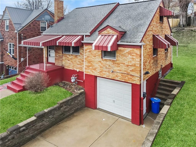 view of front of property with a shingled roof, a front yard, an attached garage, brick siding, and a chimney