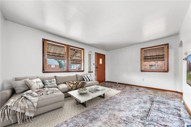 living room with baseboards, arched walkways, and carpet