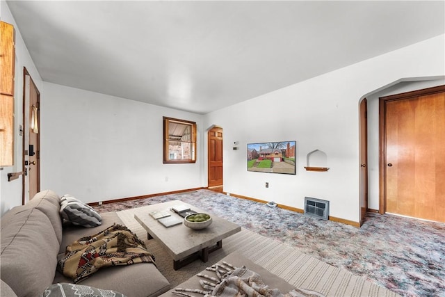 carpeted living area with baseboards and arched walkways