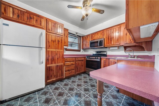 kitchen featuring a sink, stainless steel appliances, brown cabinets, and light countertops