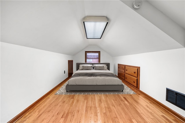 bedroom with visible vents, baseboards, vaulted ceiling, and hardwood / wood-style flooring