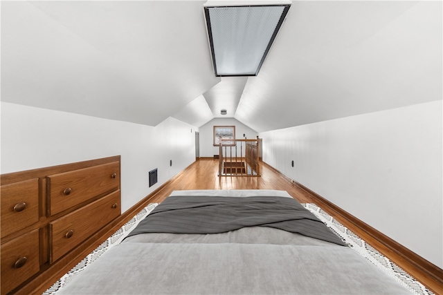 bedroom with lofted ceiling, visible vents, and light wood finished floors