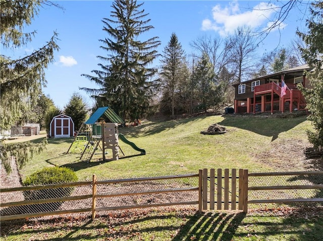 view of yard featuring an outbuilding, fence, a playground, a storage shed, and a wooden deck