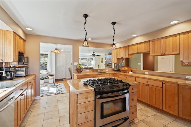 kitchen with a peninsula, light tile patterned flooring, appliances with stainless steel finishes, and a sink