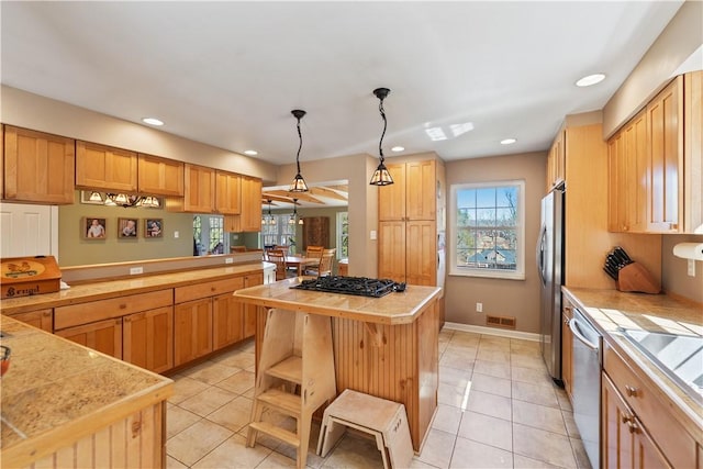 kitchen with a kitchen island, light countertops, light tile patterned floors, hanging light fixtures, and stainless steel appliances