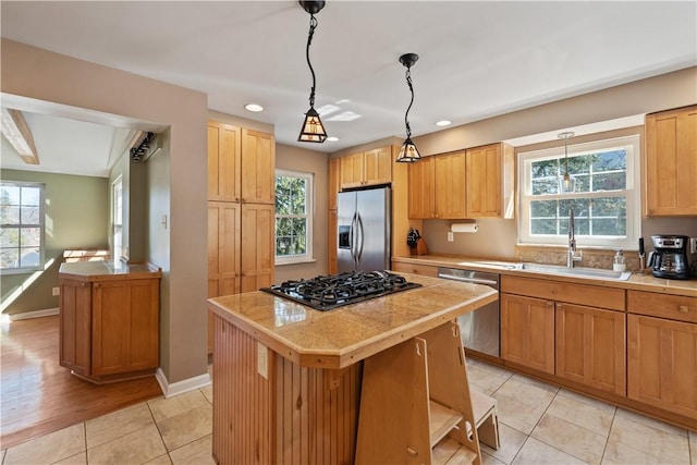 kitchen with a kitchen island, a healthy amount of sunlight, stainless steel appliances, and a sink