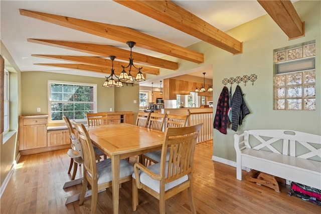 dining room with light wood finished floors, a notable chandelier, plenty of natural light, and beamed ceiling