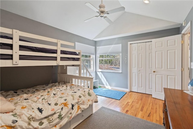 bedroom featuring light wood finished floors, ceiling fan, baseboards, vaulted ceiling, and a closet