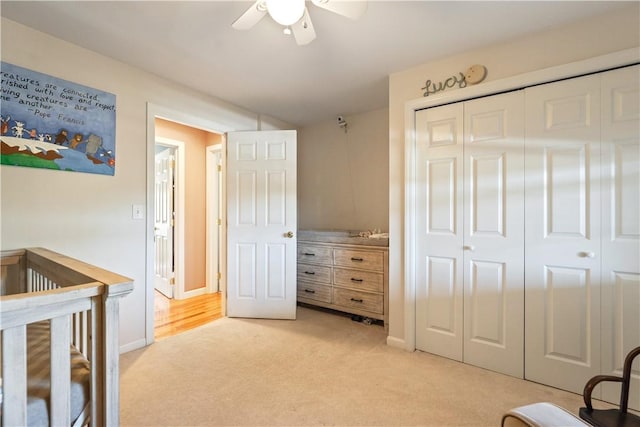 bedroom with ceiling fan, light colored carpet, a closet, and baseboards