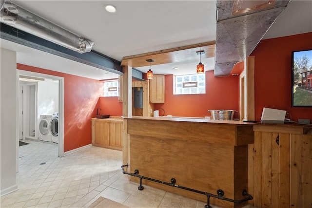 kitchen featuring pendant lighting, a peninsula, baseboards, and separate washer and dryer