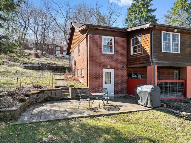 rear view of house featuring a yard, brick siding, and a patio area