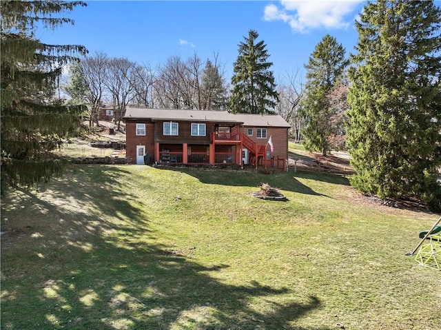 rear view of property featuring stairway, a fire pit, a deck, and a lawn