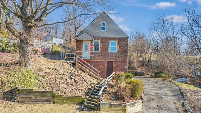 view of front of house featuring stairs, aphalt driveway, and brick siding