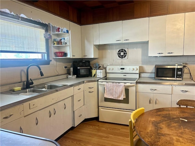 kitchen featuring white electric range oven, light wood-style flooring, a sink, decorative backsplash, and stainless steel microwave