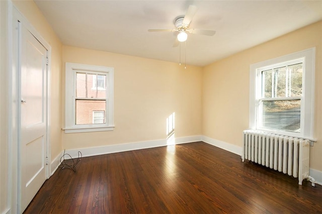 spare room featuring ceiling fan, radiator, baseboards, and hardwood / wood-style floors