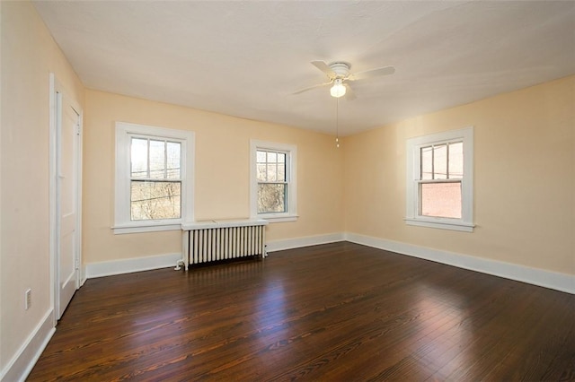 unfurnished room featuring dark wood finished floors, ceiling fan, radiator heating unit, and baseboards