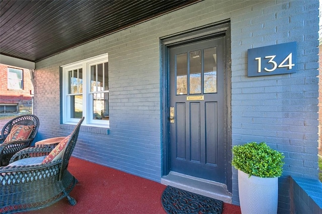 property entrance featuring brick siding and covered porch