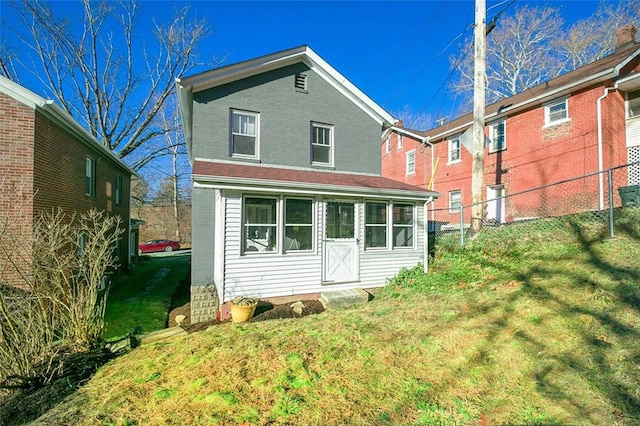 rear view of house featuring a yard, fence, and brick siding