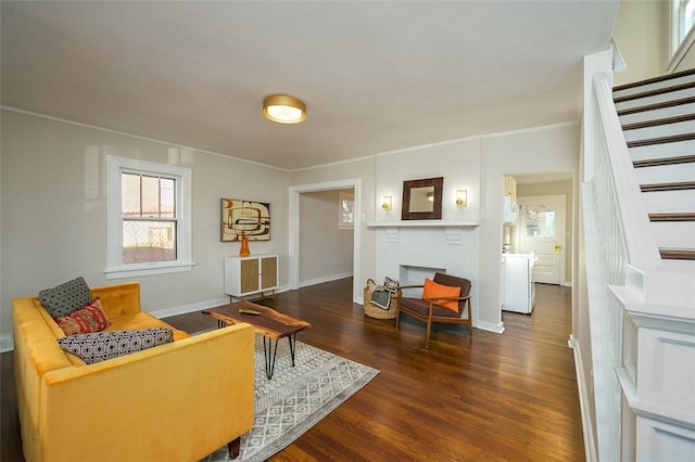 living area with baseboards, stairway, ornamental molding, a fireplace, and wood finished floors